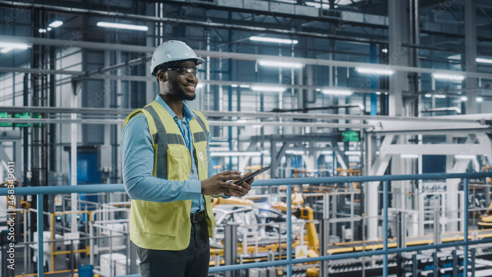 Poster happy african american car factory engineer in high visibility vest using tablet computer. automotiv