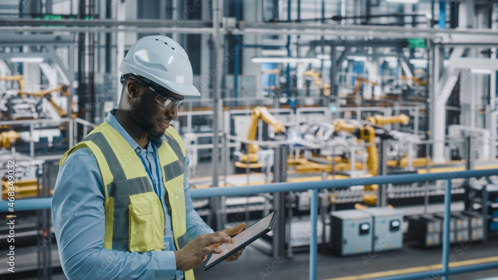 Poster happy african american car factory engineer in high visibility vest using tablet computer. automotiv