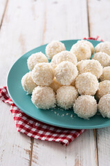 Homemade coconut balls on white wooden table	