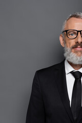 cropped view of bearded middle aged businessman in glasses and suit on grey