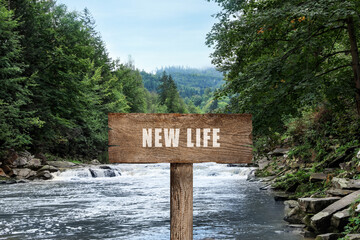 Start to live without alcohol addiction. Wooden signpost with inscription NEW LIFE near wild mountain river