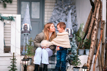 Happy little kids sitting on the porch of the Christmas decorated house outdoor