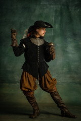 Portrait of brutal horrendous man, medeival pirate in vintage costume holding sword isolated over dark background. Swordcraft
