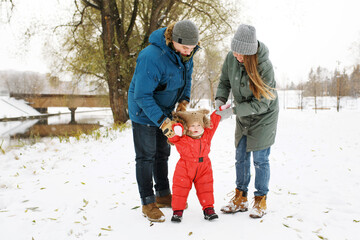 Fototapeta na wymiar Full height of happy family with one toddler in winter casual outfit walking having fun outdoors