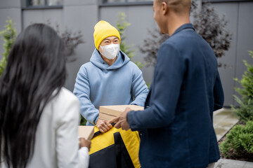 Businesspeople taking order from courier in medical mask and with bicycle. Concept of shipping and logistics during Coronavirus pandemic. Idea of break on job. Smiling men and woman