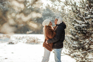 Fototapeta na wymiar Young beautiful couple in love hugging on a snowy street