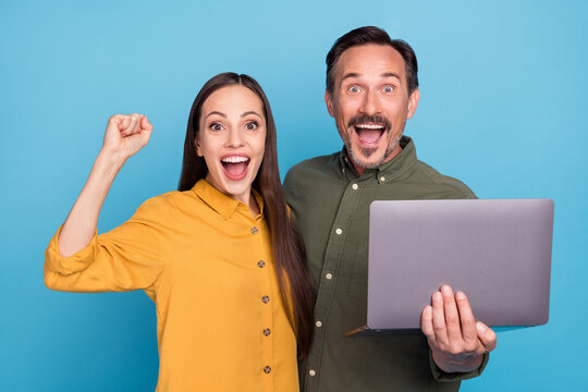 Portrait of delighted attractive lady handsome man raise fists shout yes rejoice triumph isolated on blue color background