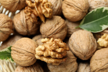 Walnuts in wicker bowl on white background