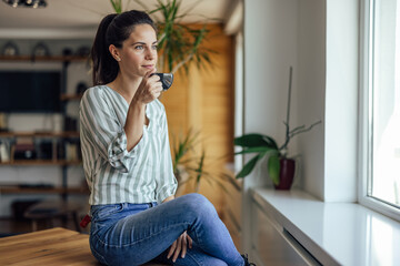 Tranquil adult woman, relaxing at home, drinking