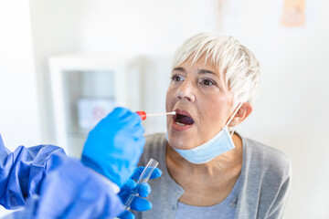 Physician wearing personal protective equipment performing a Coronavirus COVID-19 PCR test, patient...