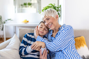 Happy senior grandmother sit on couch in living room hugging cute little preschooler grandson, smiling mature 70s granny embrace cuddle with small grandchild, show love and care, bonding concept © Graphicroyalty