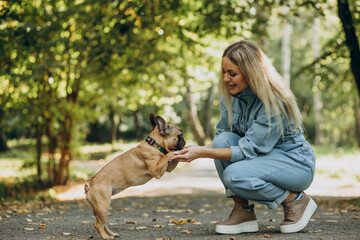 Young woman with her pet french bulldog in park