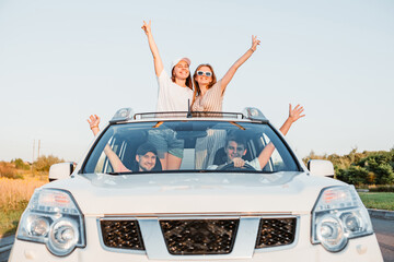 car travel. fun happy people stick put of sun roof