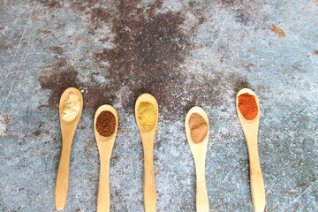 wooden spoons with spices on wooden background
