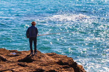 Fisherman on a rock with the sea in the background