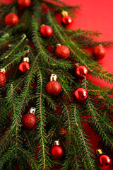 Obraz na płótnie Canvas Christmas red and green background. Pine branches, needles and Christmas tree. View from above. Nature. December mood. Red balls decor. Card for new year.