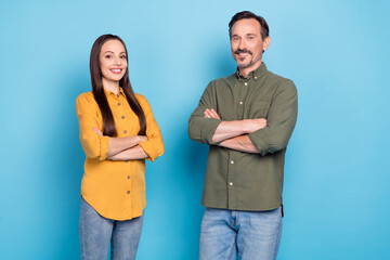 Photo of two cheerful candid persons folded hands have good mood look camera isolated on blue color...