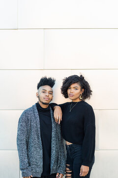 African American transgender couple not smiling, hanging out in front of blank wall with copy space, staring at the camera