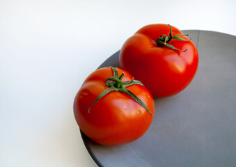 Two ripe tomatoes on grey concrete plate