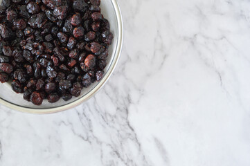 Photo of dried cranberries in a fine mesh strainer in the corner of a marble kitchen counter