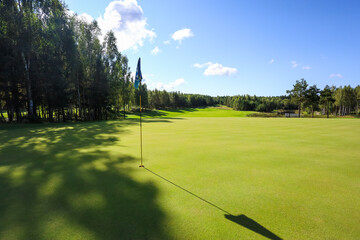 Obraz premium Flag shadow on the golf course with green grass. High quality photo