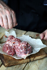 Soft focus. The chef's hand is salting raw lamb.