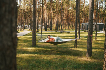 Smiling man with tablet relaxing in hammock