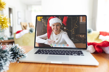 Smiling caucasian woman in santa hat on laptop christmas video call interface screen