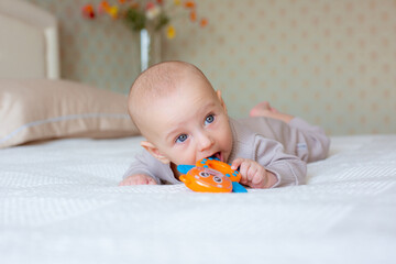 baby boy with a rattle on the bed