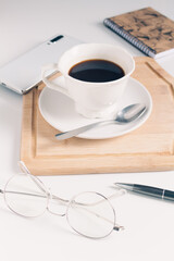 Cup of coffee and office supplies on white table. 