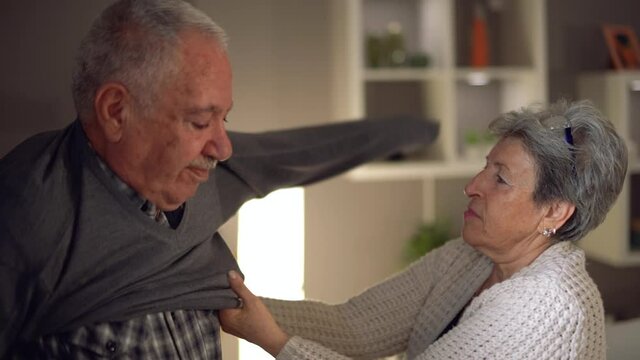 Dressing up old man.
The old woman helps her husband put on his clothes. Elderly states. Get old. Slow motion.