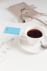 Cup of coffee, purse, glasses and credit card on white table. Cafe concept.