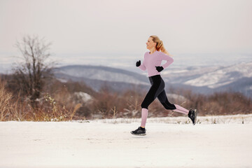 Fast sportswoman sprinting in nature at snowy winter day. Healthy life, healthy habits, winter fitness
