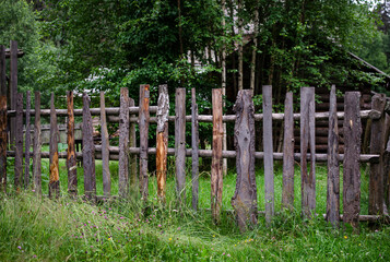 Old fence on a farm made of boards and branches