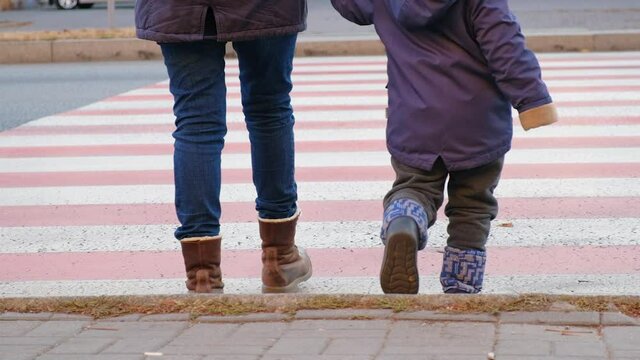 Mom and child cross the road at the zebra crossing.