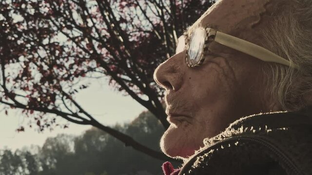 Face of an elderly woman with dementia and paralysis in the sunset.