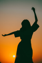 Vertical silhouette of a woman dancing at sunset 