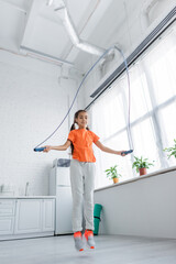 Fototapeta na wymiar Low angle view of preteen kid training with jump rope at home