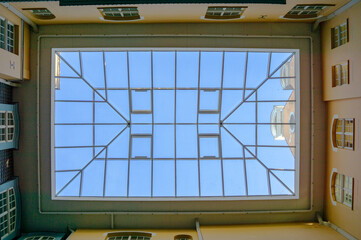 View of the glass roof of the house from the courtyard. View through the glass roof to the blue sky.
