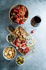 traditional Spanish or Italian tapas. jamon iberico, blue cheese, crackers, olives, grapes and dry red wine,  grey stone background. Top view