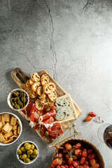 traditional Spanish or Italian tapas. jamon iberico, blue cheese, crackers, olives, grapes and dry red wine,  grey stone background. Top view