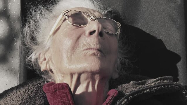 Elderly woman with dementia and paralysis sitting in the setting sun.