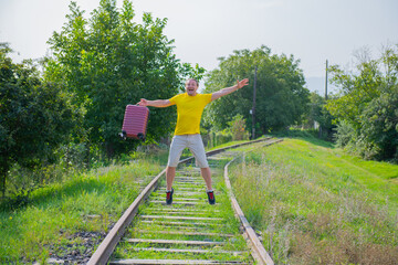 guy with a suitcase jumping on the railroad