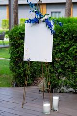 Wedding board, mockup, invitation easel, with space for an inscription, decorated with fresh flowers. Festive decor, copy space. Soft selective focus.
