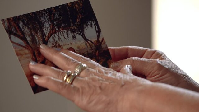 Aged hands on the photo.
The old woman runs her fingers over an ancient photograph. Slow motion.