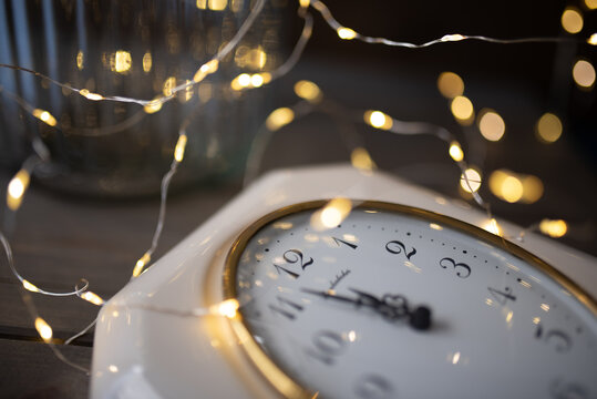 A view of new year clock before midnight with garland lights.