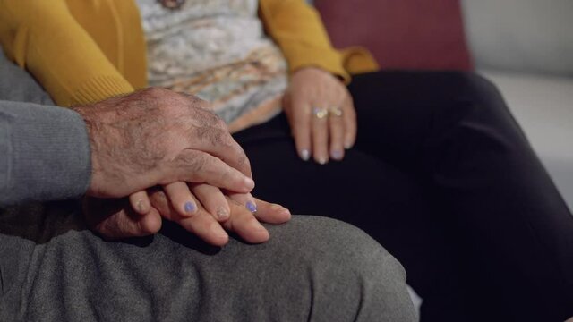 Long years of love. Old woman putting her hands on her husband's hand. A happy and peaceful marriage. Slow motion.