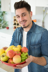 healthy young man holding a bowl of fruit