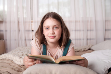 10-year-old girl lying on   stomach on   bed with   book.