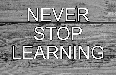 never stop learning white letters wooden background